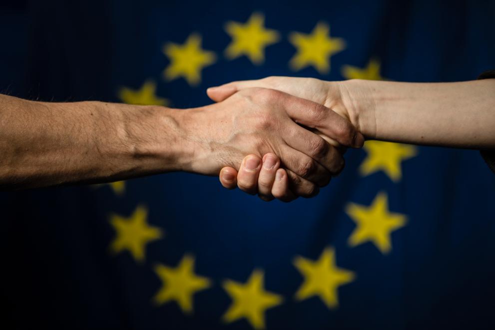 Illustration: Poignée de main devant le drapeau européen