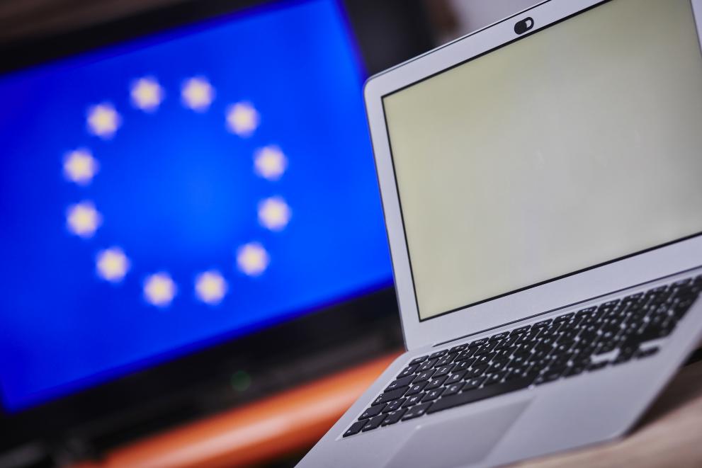   Un ordinateur avec écran blanc et le drapeau Européen en arrière-plan